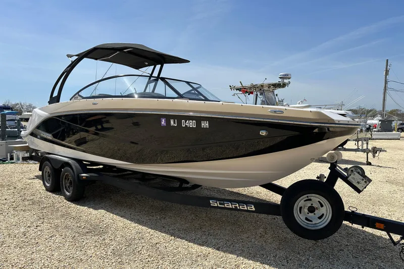 Slide: The Image of 2016 Scarab 255 H.O. Platinum boat on trailer, displayed outdoors under clear sky. - 2