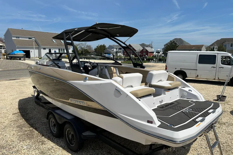 Slide: The Image of 2016 Scarab 255 H.O. Platinum boat on trailer, parked in residential area under clear sky. - 5