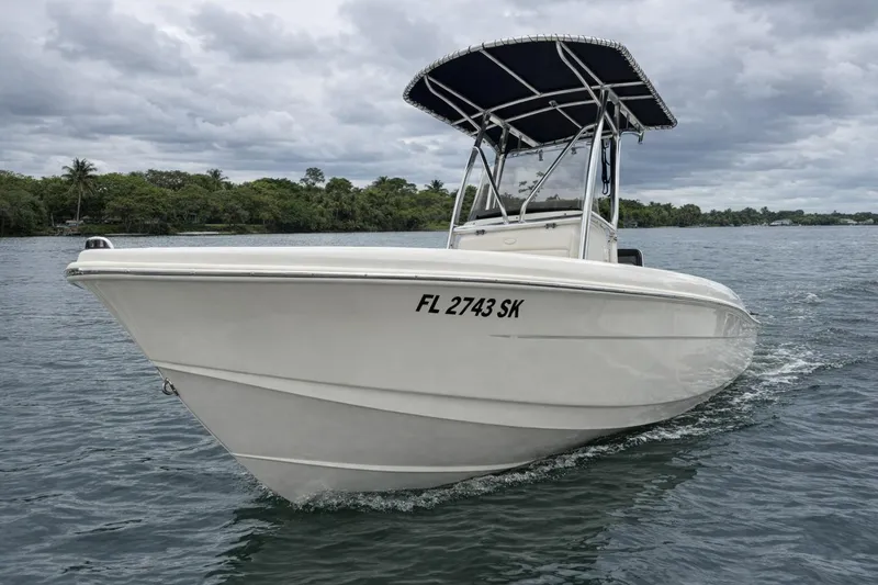 The Image of 2013 Scout 210 XSF boat cruising on a calm lake under cloudy skies. - 0