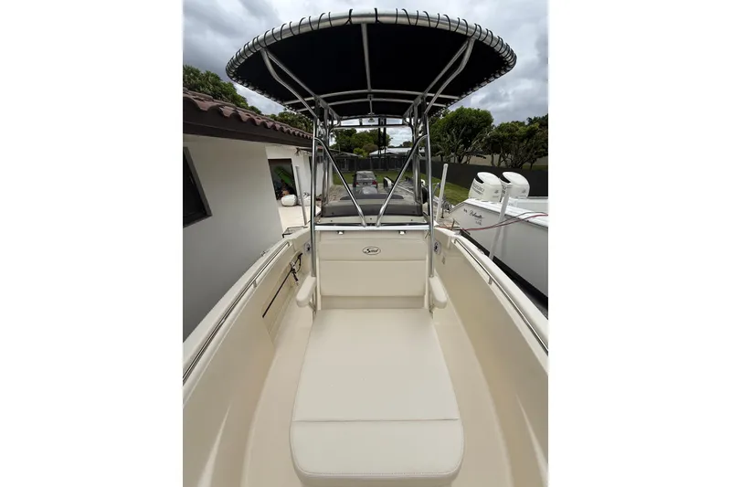 Slide: The Image of 2013 Scout 210 XSF boat with T-top, beige seating, and sleek design. - 12