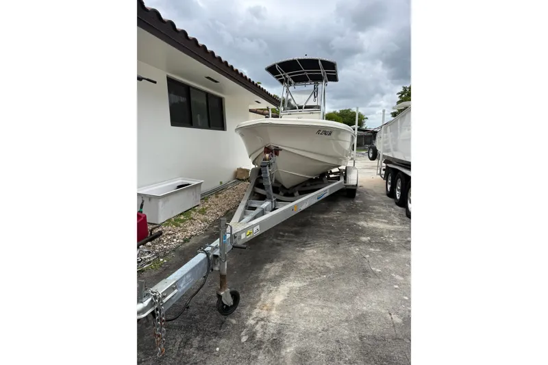 Slide: The Image of 2013 Scout 210 XSF boat on trailer beside a building under cloudy skies. - 13