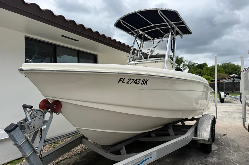 Slide: The Image of 2013 Scout 210 XSF boat on trailer, parked near a house under cloudy skies. - 15