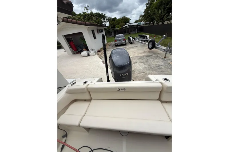 Slide: The Image of 2013 Scout 210 XSF boat with Yamaha 150 engine, parked near a house and trailer. - 8