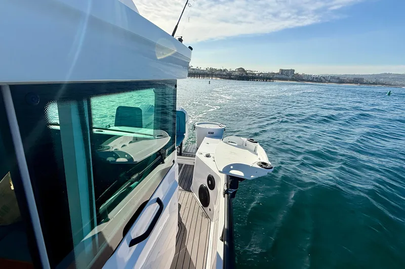 Slide: The Image of 2021 Axopar Brabus 28 Cabin cruising on a sunny day near a coastal city. - 13