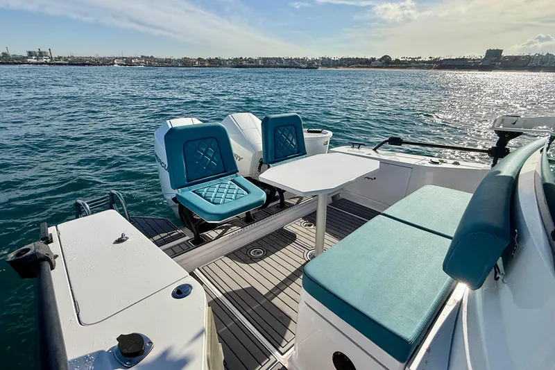 Slide: The Image of 2021 Axopar Brabus 28 Cabin boat interior with turquoise seating and table on open water. - 19