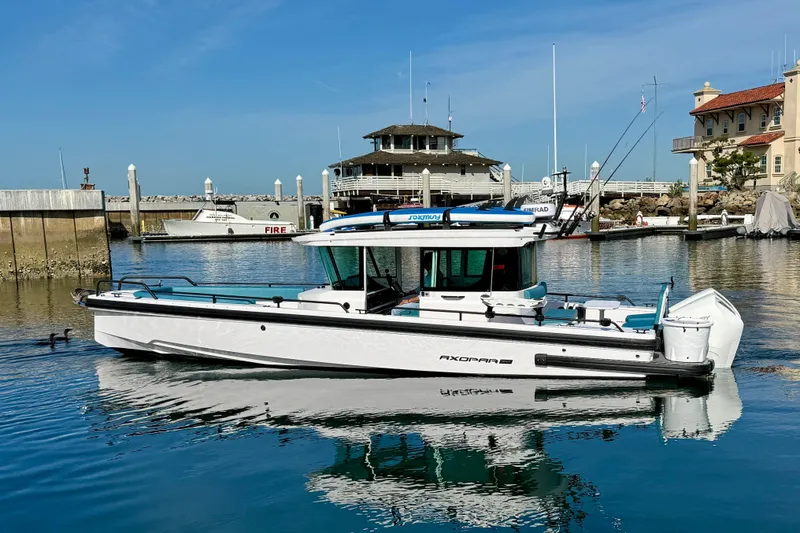 Slide: The Image of 2021 Axopar Brabus 28 Cabin boat docked in a marina under clear blue skies. - 2