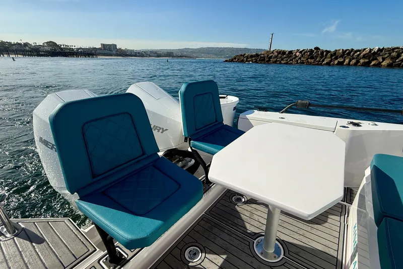 Slide: The Image of 2021 Axopar Brabus 28 Cabin boat interior with blue seats and table on the water. - 20