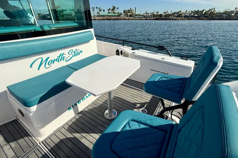 Slide: The Image of 2021 Axopar Brabus 28 Cabin boat interior with teal seating and table on water. - 22
