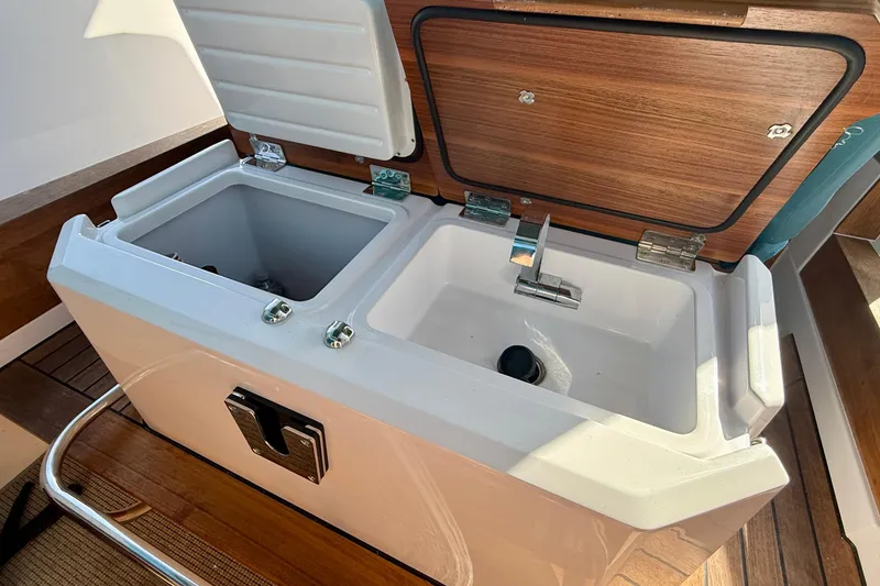 Slide: The Image of Open storage compartment on 2021 Axopar Brabus 28 Cabin boat, featuring dual sinks and wooden accents. - 55