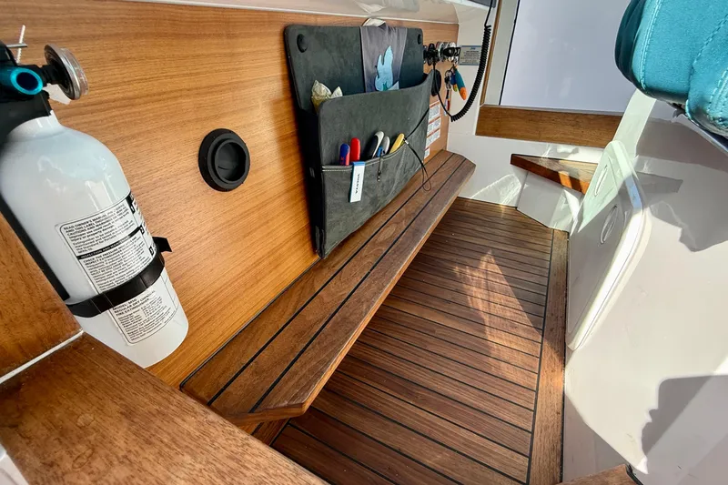 Slide: The Image of 2021 Axopar Brabus 28 Cabin interior with wooden flooring and mounted fire extinguisher. - 56