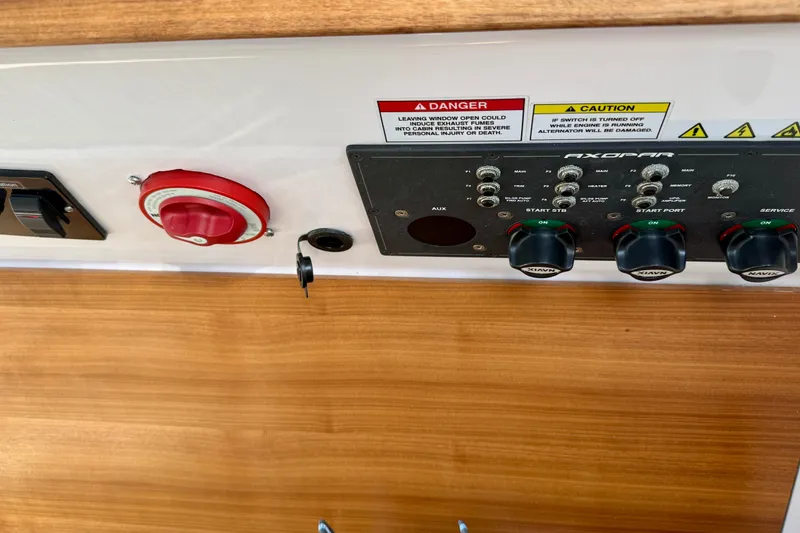 Slide: The Image of Control panel of 2021 Axopar Brabus 28 Cabin with switches and warning labels. - 58
