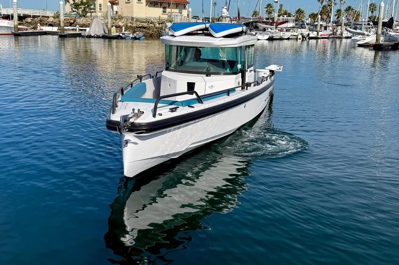 Slide: The Image of 2021 Axopar Brabus 28 Cabin boat cruising in a marina with clear blue water. - 6