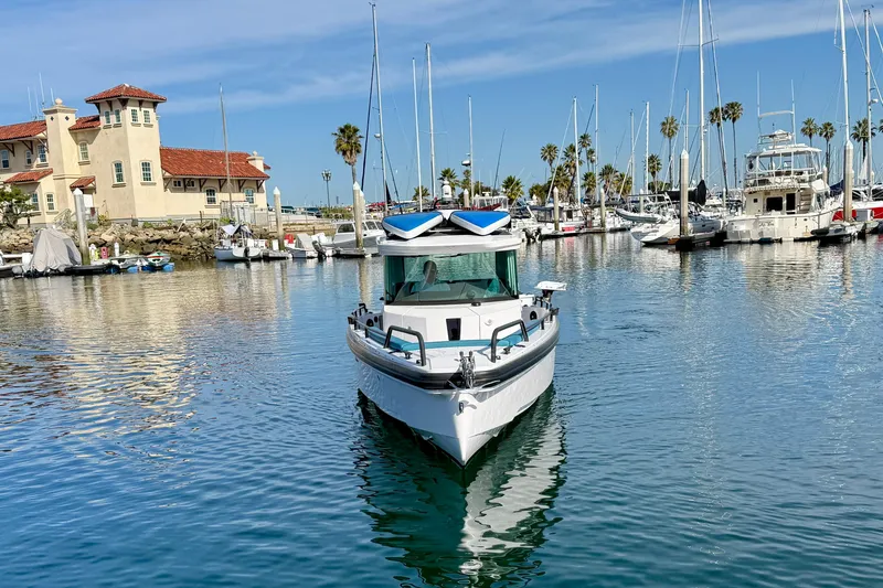 Slide: The Image of 2021 Axopar Brabus 28 Cabin boat docked in a scenic marina with sailboats. - 7