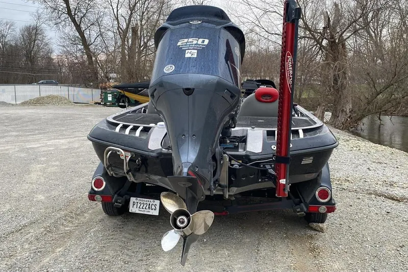 Slide: The Image of 2011 Ranger Z520 boat with powerful outboard motor, parked on gravel near trees. - 4