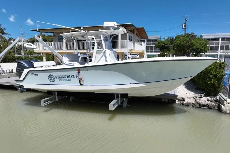 The Image of 2006 SeaVee 290B boat docked near waterfront home under clear blue sky. - 0