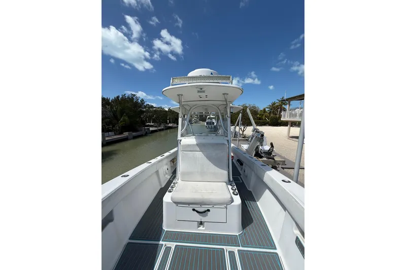Slide: The Image of 2006 SeaVee 290B boat docked, featuring spacious deck and center console under clear blue sky. - 27