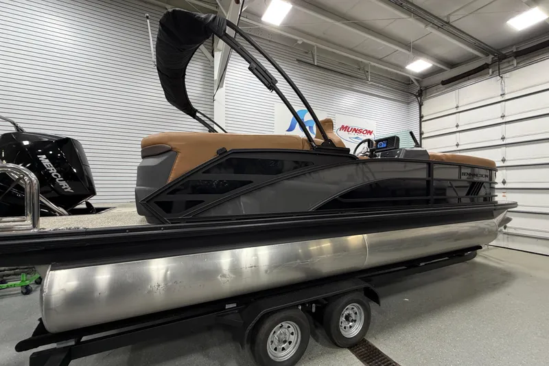 Slide: The Image of 2025 Bennington M Quad Bench 24 MFB pontoon boat in showroom, featuring sleek design and Mercury engine. - 3