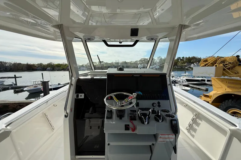 Slide: The Image of 2026 Pursuit S 358 Sport boat cockpit with steering wheel and controls, docked at marina. - 11