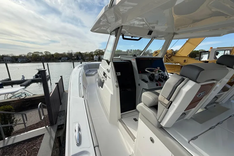 Slide: The Image of 2026 Pursuit S 358 Sport boat interior with helm and seating, docked by a serene waterfront. - 13