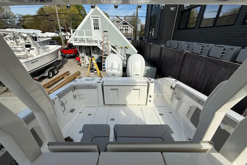 Slide: The Image of 2026 Pursuit S 358 Sport boat interior with dual engines, docked near a workshop. - 6