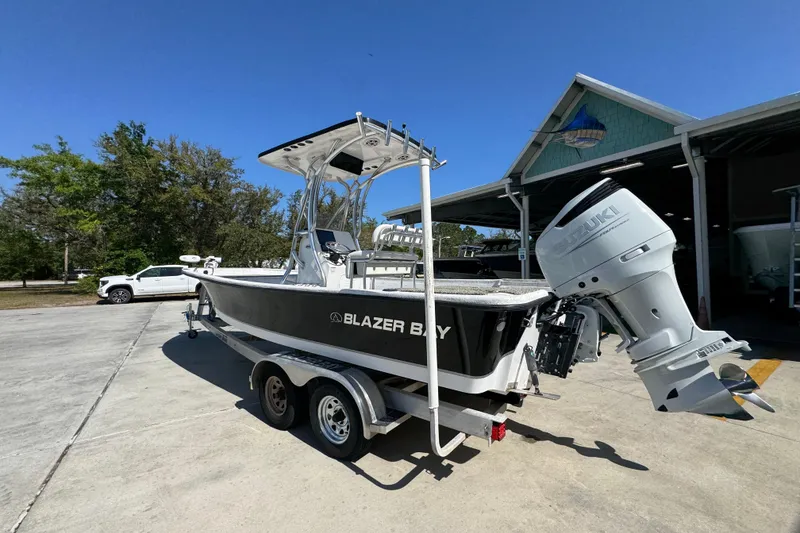 Slide: The Image of 2021 Blazer Bay 2400 boat with Suzuki outboard motor on trailer, parked outdoors. - 17