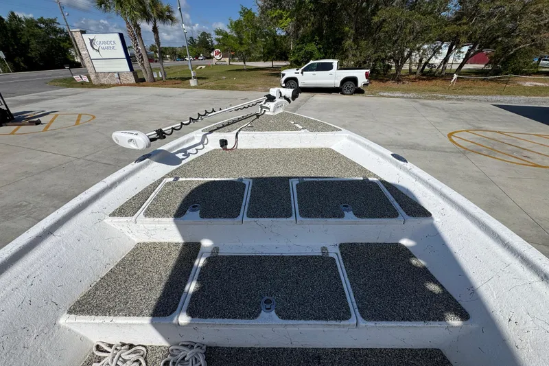 Slide: The Image of 2021 Blazer Bay 2400 boat deck with storage compartments and trolling motor in parking lot. - 19