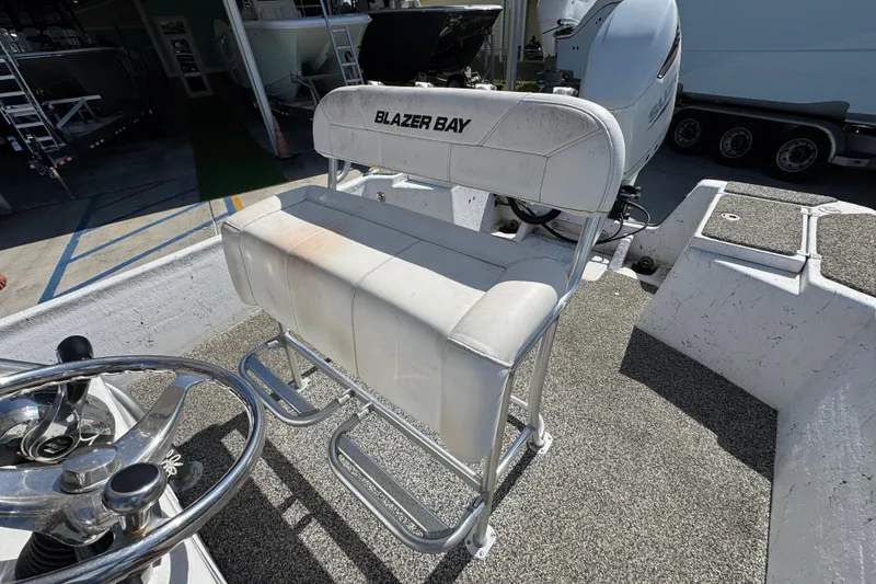 Slide: The Image of 2021 Blazer Bay 2400 boat seat and steering wheel in a marina setting. - 28