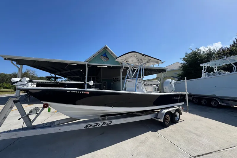 Slide: The Image of 2021 Blazer Bay 2400 boat on trailer, parked outdoors under clear blue sky. - 3