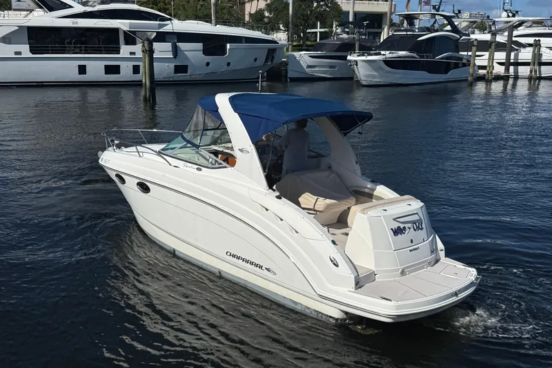 Slide: The Image of 2009 Chaparral Signature 250 boat docked in marina, featuring sleek white design and blue canopy. - 2