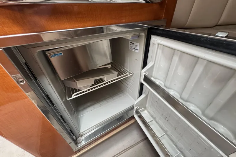 Slide: The Image of Open refrigerator inside 2009 Chaparral Signature 250 boat, featuring wooden cabinetry. - 40