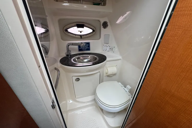 Slide: The Image of 2009 Chaparral Signature 250 boat bathroom with sink, toilet, and porthole window. - 41