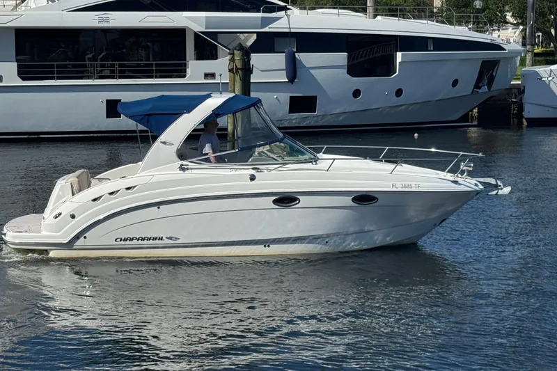 Slide: The Image of 2009 Chaparral Signature 250 boat cruising near a marina with a luxury yacht in the background. - 5