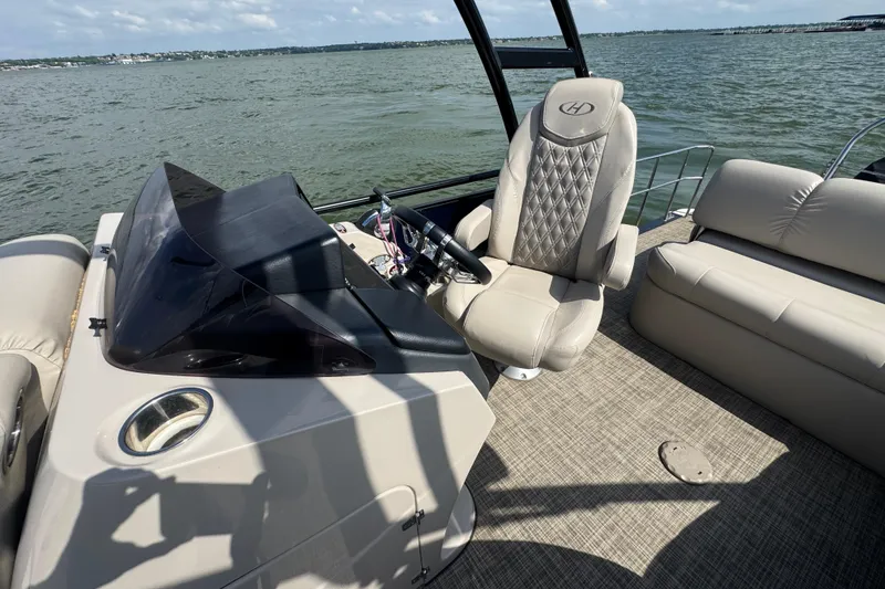 Slide: The Image of 2019 Harris Solstice 220 boat interior with steering console and plush seating on a lake. - 14