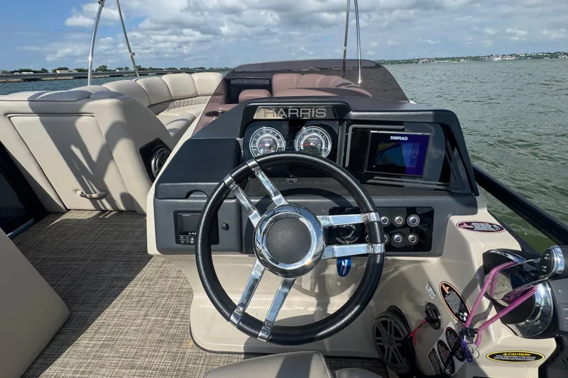 Slide: The Image of 2019 Harris Solstice 220 boat dashboard with steering wheel and navigation system on a lake. - 16