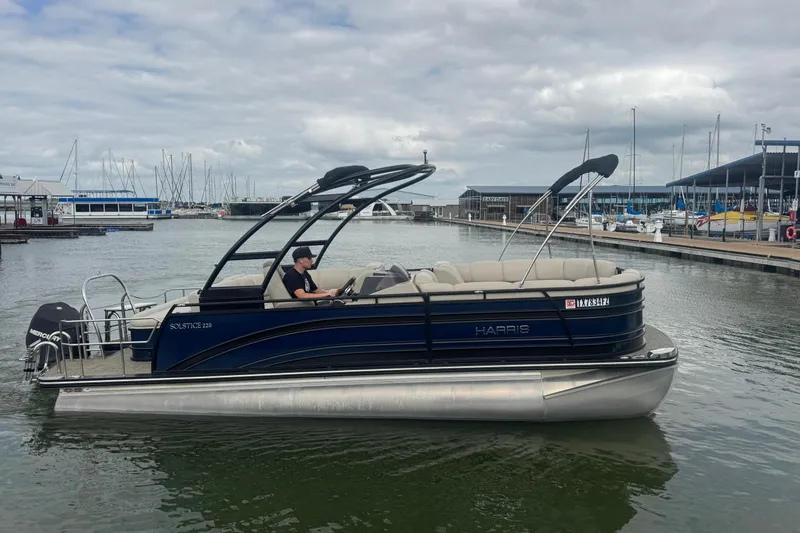 Slide: The Image of 2019 Harris Solstice 220 pontoon boat on calm marina waters under cloudy skies. - 6