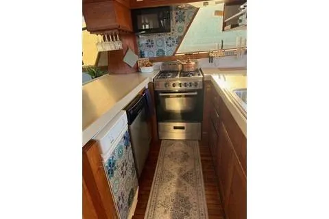 Slide: The Image of 1982 Kong & Halvorsen Island Gypsy yacht kitchen with stove, wooden cabinets, and decorative tiles. - 64