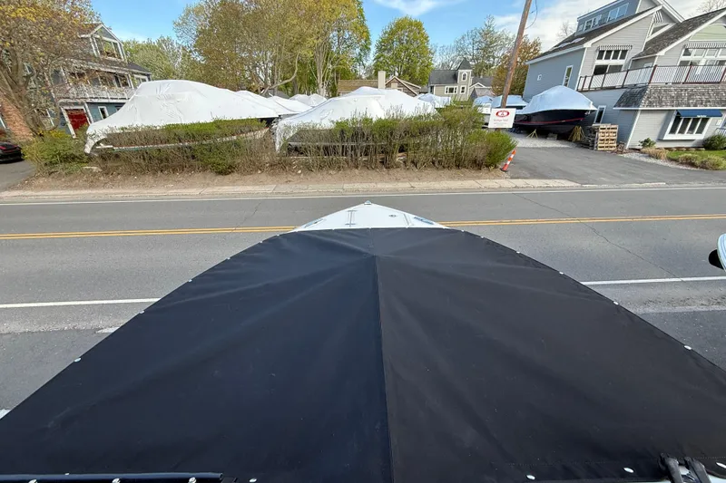 Slide: The Image of 2026 Pursuit DC 266 Dual Console boat with cover, parked near residential area. - 13