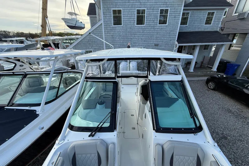 Slide: The Image of 2026 Pursuit DC 266 Dual Console boat docked near coastal homes. - 14