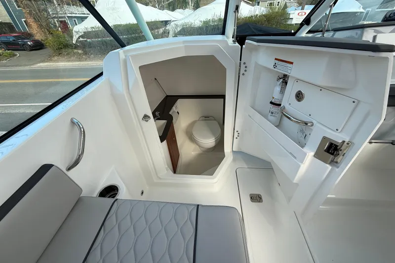 Slide: The Image of 2026 Pursuit DC 266 Dual Console boat interior with compact marine toilet. - 8