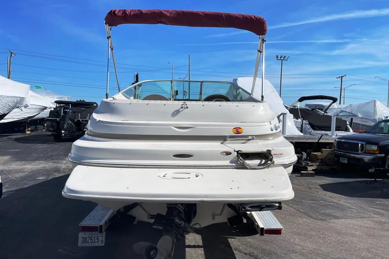 Slide: The Image of 2001 Maxum 2300 SR boat with red canopy, parked outdoors under blue sky. - 2