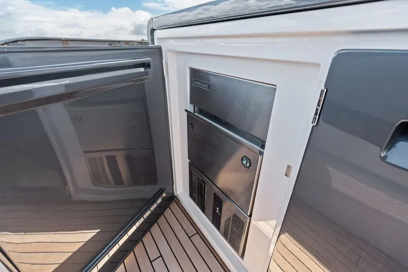 Slide: The Image of Sunseeker 88 Yacht 2026, open stainless steel refrigerator on teak deck. - 34