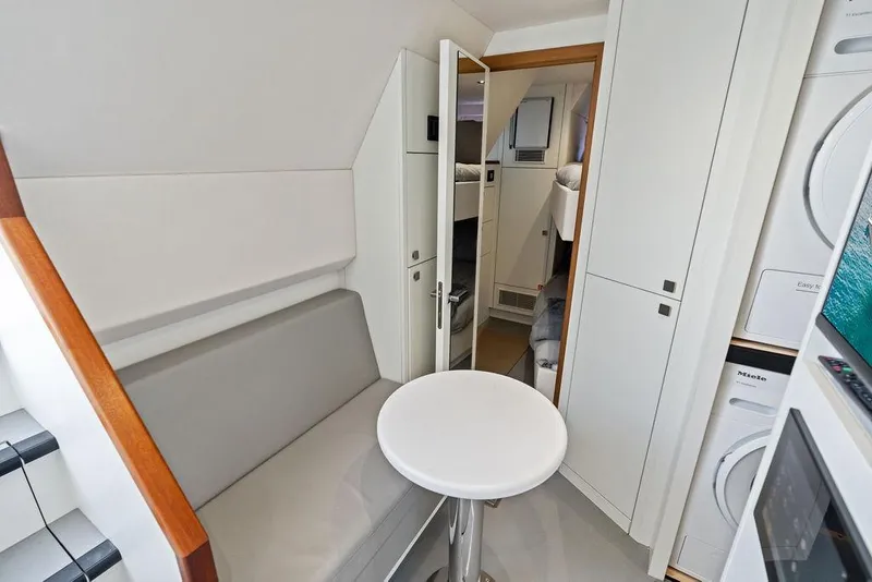 Slide: The Image of Interior of 2026 Sunseeker 88 Yacht featuring modern seating and compact laundry area. - 99