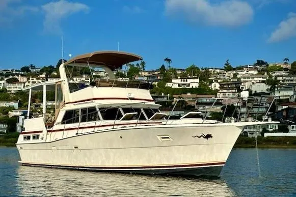 Slide: The Image of 1980 Viking 43 Convertible yacht docked at a marina with modern buildings in the background. - 7