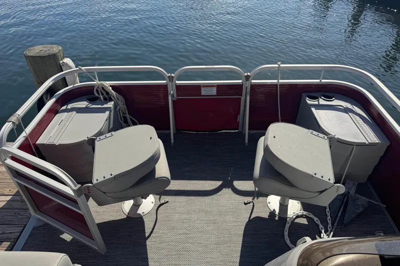Slide: The Image of 2023 Bennington 188 SVF pontoon boat interior with seating and storage, docked by water. - 11