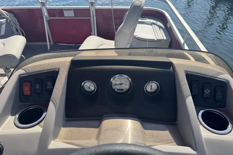 Slide: The Image of 2023 Bennington 188 SVF boat dashboard with gauges and controls, overlooking water. - 8
