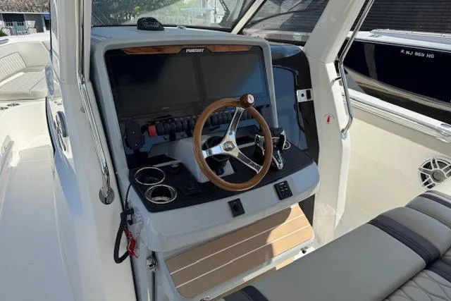 Slide: The Image of 2026 Pursuit S 328 Sport boat cockpit with modern steering and controls. - 13