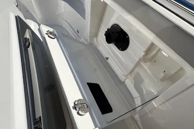 Slide: The Image of 2026 Pursuit S 328 Sport boat storage compartment with open hatch and secure latches. - 20