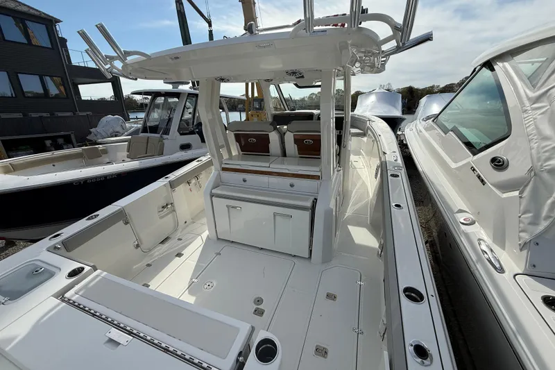 Slide: The Image of 2026 Pursuit S 328 Sport boat interior with seating and storage, docked alongside other boats. - 37