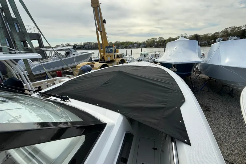 Slide: The Image of 2026 Pursuit S 328 Sport boat with black cover, docked near other boats. - 39