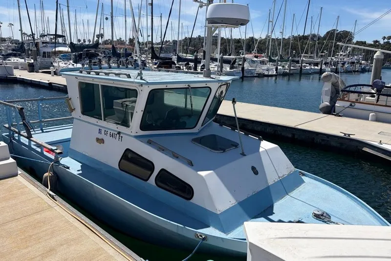 Slide: The Image of 1976 Wilson 24 boat docked at a marina with sailboats in the background. - 4